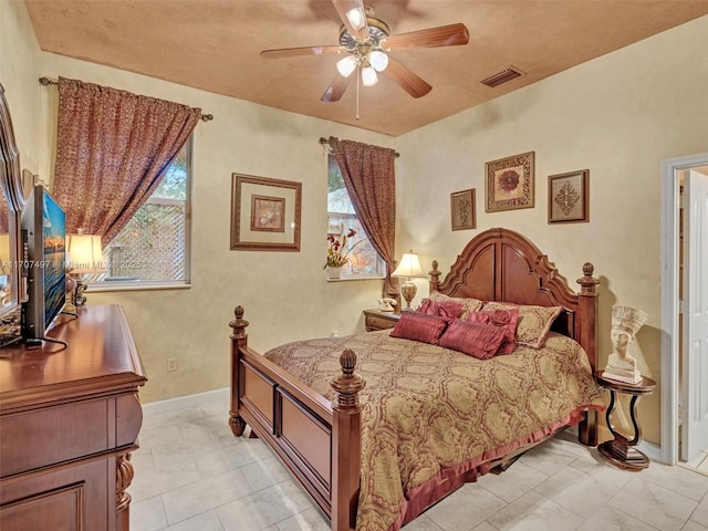 bedroom with ceiling fan, light tile patterned floors, a wood stove, and multiple windows