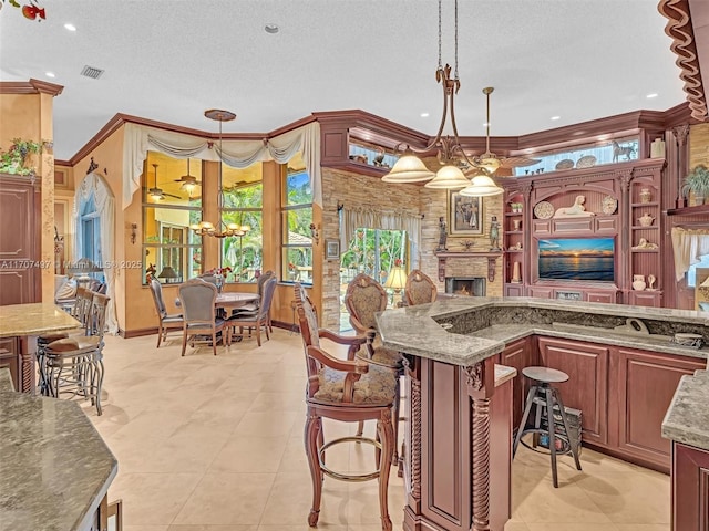 kitchen featuring stone counters, ornamental molding, pendant lighting, and a fireplace