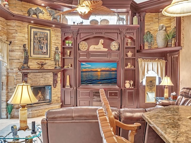 living area with ceiling fan, built in features, and a stone fireplace