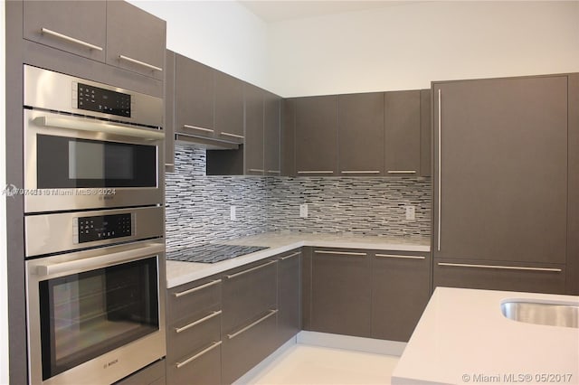 kitchen with decorative backsplash, black electric cooktop, and double oven
