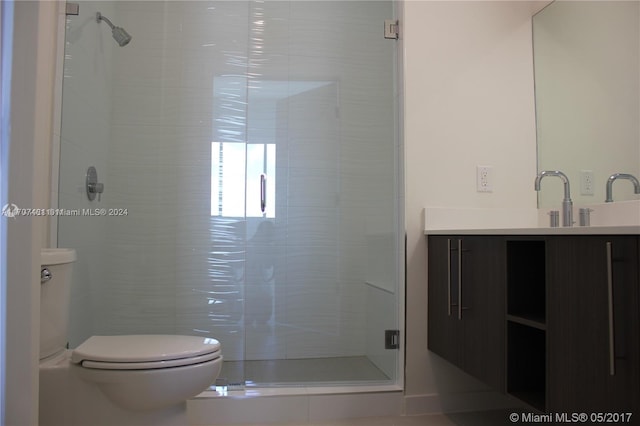 bathroom featuring vanity, toilet, and a shower with shower door