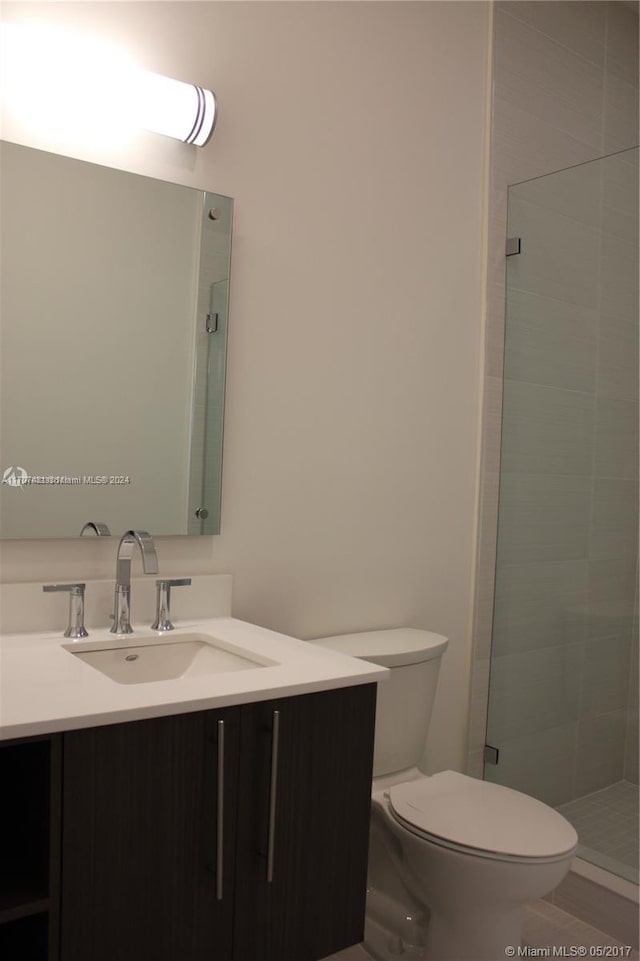 bathroom featuring a tile shower, vanity, and toilet