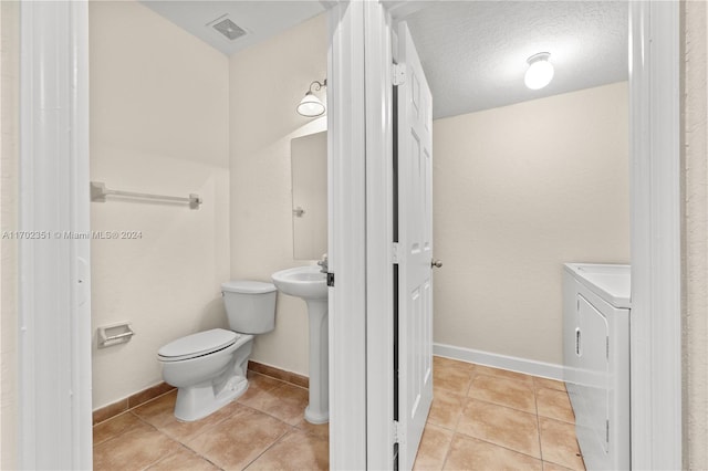 bathroom with tile patterned floors, washer and dryer, a textured ceiling, and toilet