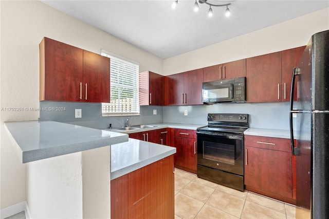 2557 SE 14th St, Homestead, FL 33035 - kitchen with black appliances, a peninsula, light countertops, light tile patterned floors, and reddish brown cabinets