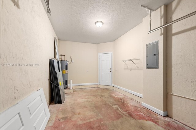 basement featuring electric water heater, a textured ceiling, and electric panel