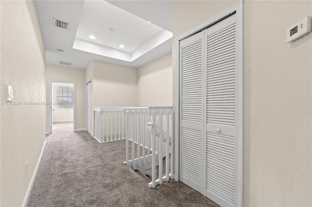 corridor featuring carpet floors and a raised ceiling