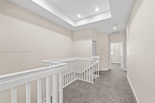 hallway featuring a raised ceiling and carpet floors