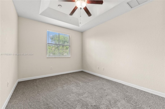 empty room featuring carpet floors, a raised ceiling, and ceiling fan