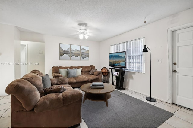 living room with ceiling fan, light tile patterned floors, and a textured ceiling