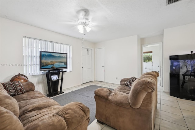 living room featuring a textured ceiling, ceiling fan, and light tile patterned flooring