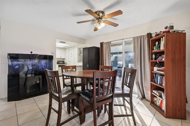 dining room featuring ceiling fan, light tile patterned floors, and a textured ceiling