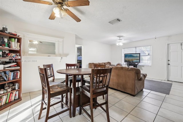 dining area featuring a textured ceiling, ceiling fan, and light tile patterned flooring