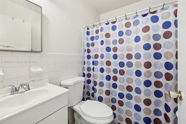 bathroom with walk in shower, vanity, tile walls, and toilet