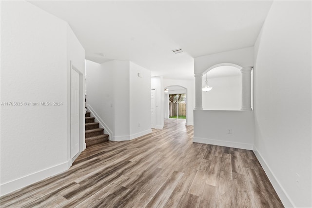 empty room featuring decorative columns and hardwood / wood-style floors