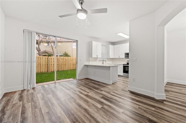 kitchen with kitchen peninsula, white cabinets, stainless steel appliances, and light wood-type flooring