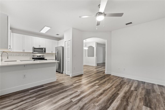 1476 SE 26th Ave, Homestead, FL 33035 - kitchen with appliances with stainless steel finishes, arched walkways, light countertops, wood finished floors, and white cabinetry