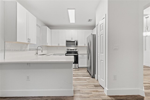 1476 SE 26th Ave, Homestead, FL 33035 - kitchen with stainless steel appliances, a peninsula, light wood-type flooring, white cabinets, and light countertops
