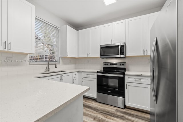 kitchen featuring white cabinets, sink, decorative backsplash, light wood-type flooring, and stainless steel appliances