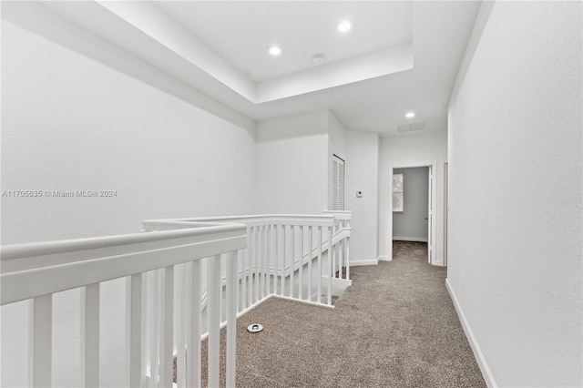 hallway with carpet floors and a tray ceiling