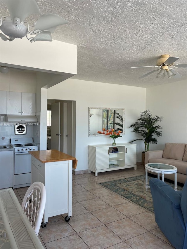 kitchen with white cabinets, stove, light tile patterned floors, and washer and clothes dryer