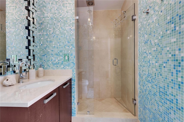 bathroom with vanity, toilet, tile walls, and walk in shower