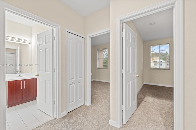 hallway featuring light carpet and sink