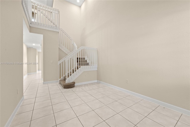 staircase featuring a high ceiling and tile patterned floors