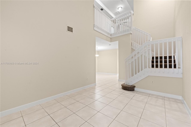 staircase featuring a towering ceiling and tile patterned floors