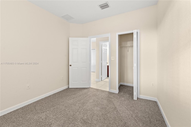 unfurnished bedroom with light colored carpet and a closet