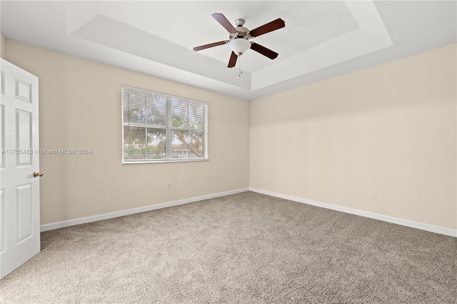 carpeted spare room featuring ceiling fan and a tray ceiling