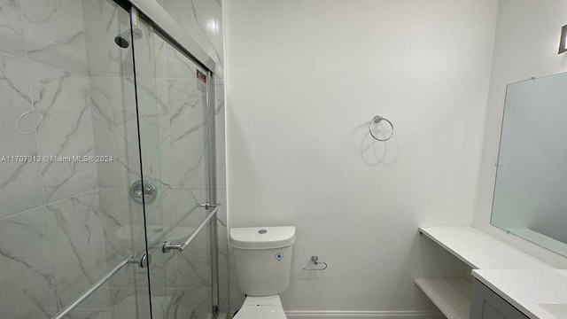 bathroom featuring vanity, a shower with shower door, and toilet