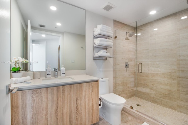 bathroom with tile patterned flooring, vanity, toilet, and a shower with shower door