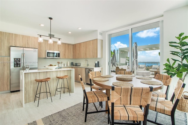 dining space featuring light hardwood / wood-style flooring, a water view, and sink