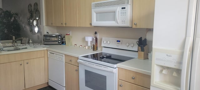 kitchen with light brown cabinetry, white appliances, and sink