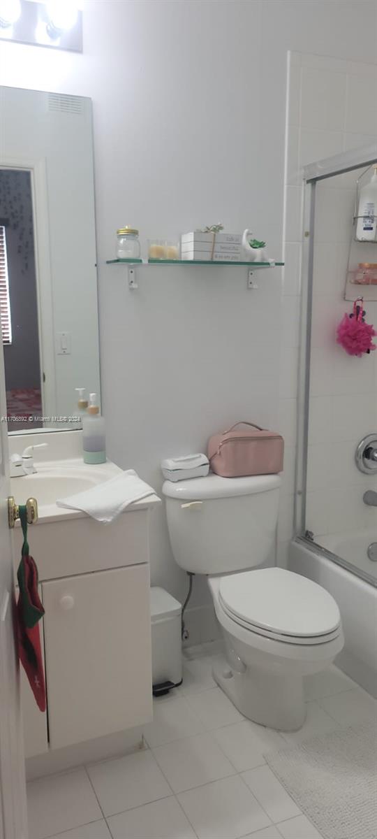 full bathroom with tile patterned flooring, vanity, toilet, and combined bath / shower with glass door