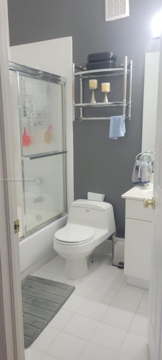 bathroom featuring tile patterned flooring, toilet, and enclosed tub / shower combo