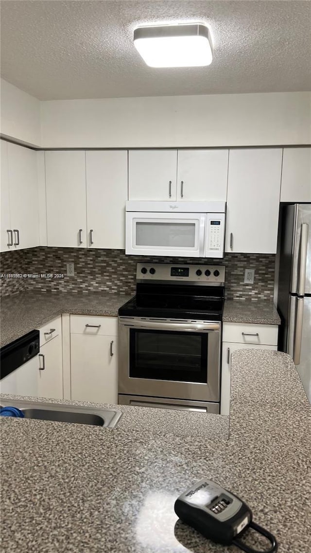 kitchen with appliances with stainless steel finishes, white cabinets, a textured ceiling, and decorative backsplash