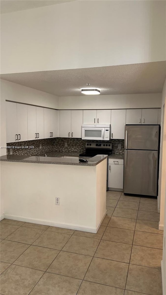 kitchen featuring backsplash, stainless steel appliances, light tile patterned floors, and white cabinets