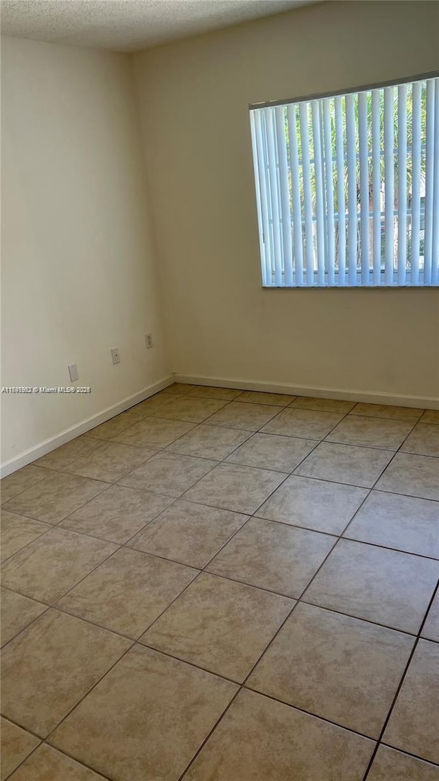 tiled spare room with a textured ceiling