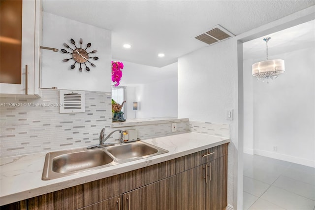 kitchen featuring decorative backsplash, light tile patterned floors, hanging light fixtures, and sink