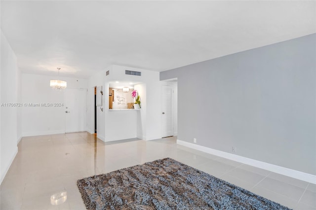 empty room featuring light tile patterned flooring and a chandelier