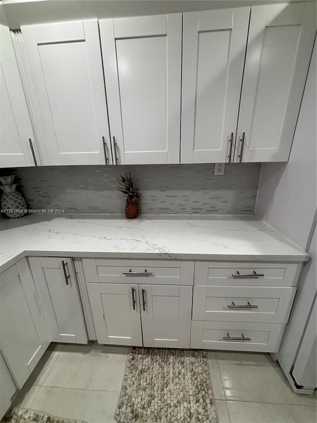 kitchen featuring tasteful backsplash, light stone counters, and light tile patterned flooring