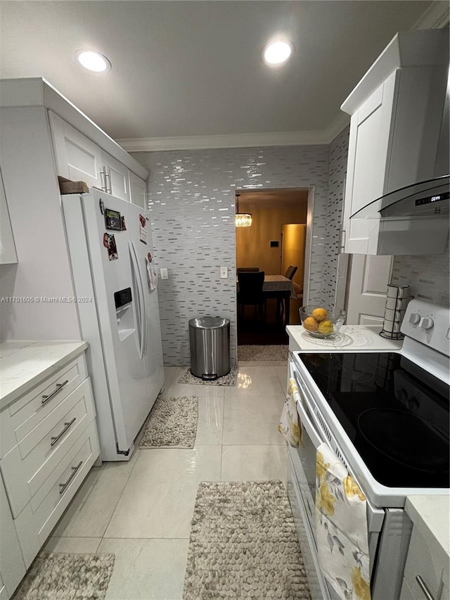 kitchen with wall chimney range hood, white cabinetry, white appliances, and ornamental molding