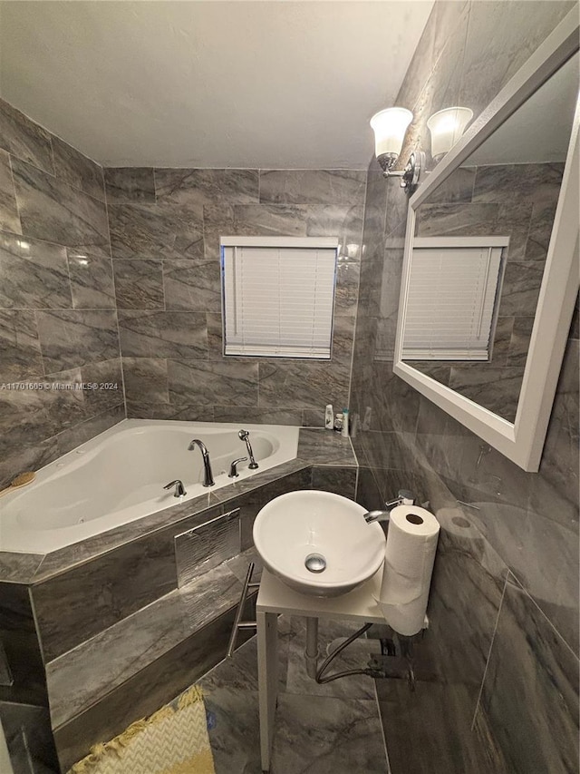 bathroom featuring tiled tub, sink, and tile walls