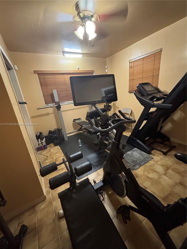 exercise room with ceiling fan and tile patterned flooring