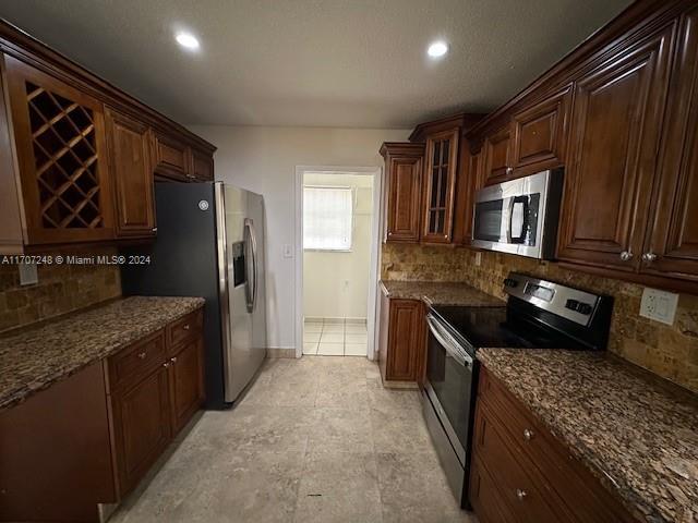 kitchen featuring dark stone countertops, appliances with stainless steel finishes, and tasteful backsplash