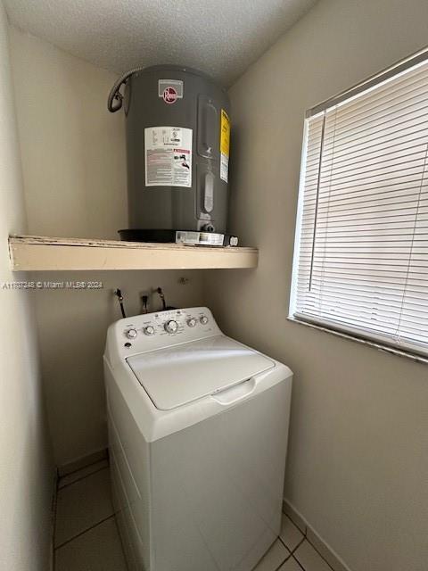 washroom with washer / dryer, a textured ceiling, and light tile patterned floors