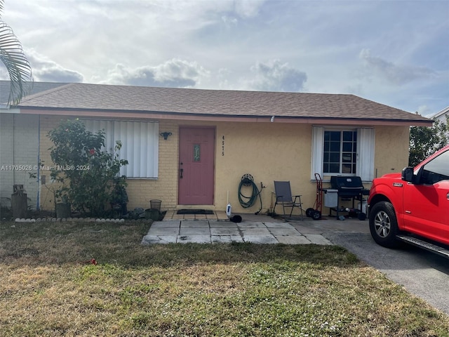 4575 Gladiator Cir, Green Acres, FL 33463 - view of front of property featuring a front lawn, roof with shingles, brick siding, and stucco siding