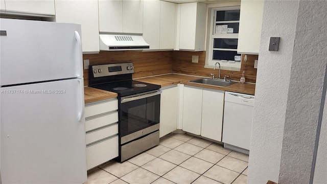 kitchen with sink, light tile patterned floors, white appliances, white cabinets, and exhaust hood