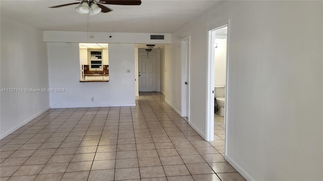 spare room with ceiling fan, light tile patterned floors, and a textured ceiling